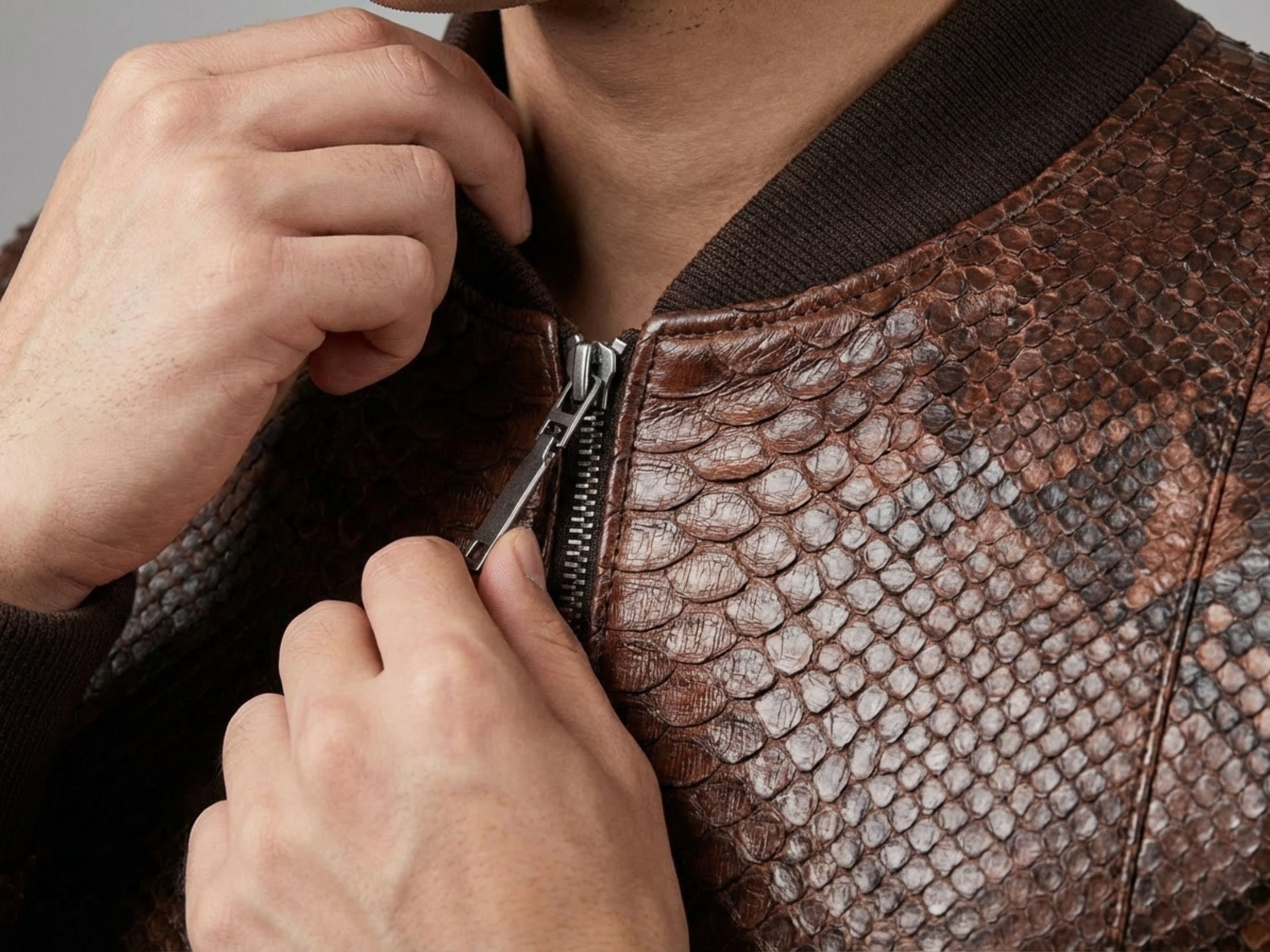 Close-up of brown snakeskin leather bomber jacket zip and textured leather