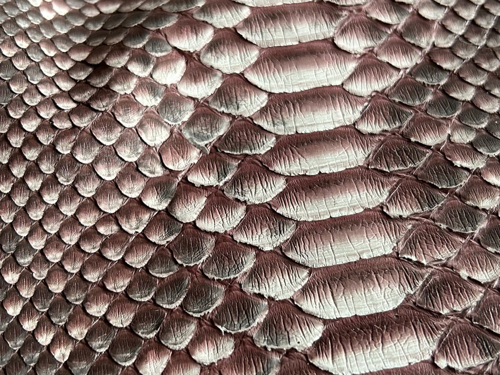Burgundy snakeskin texture on leather jacket surface, scale pattern detail.