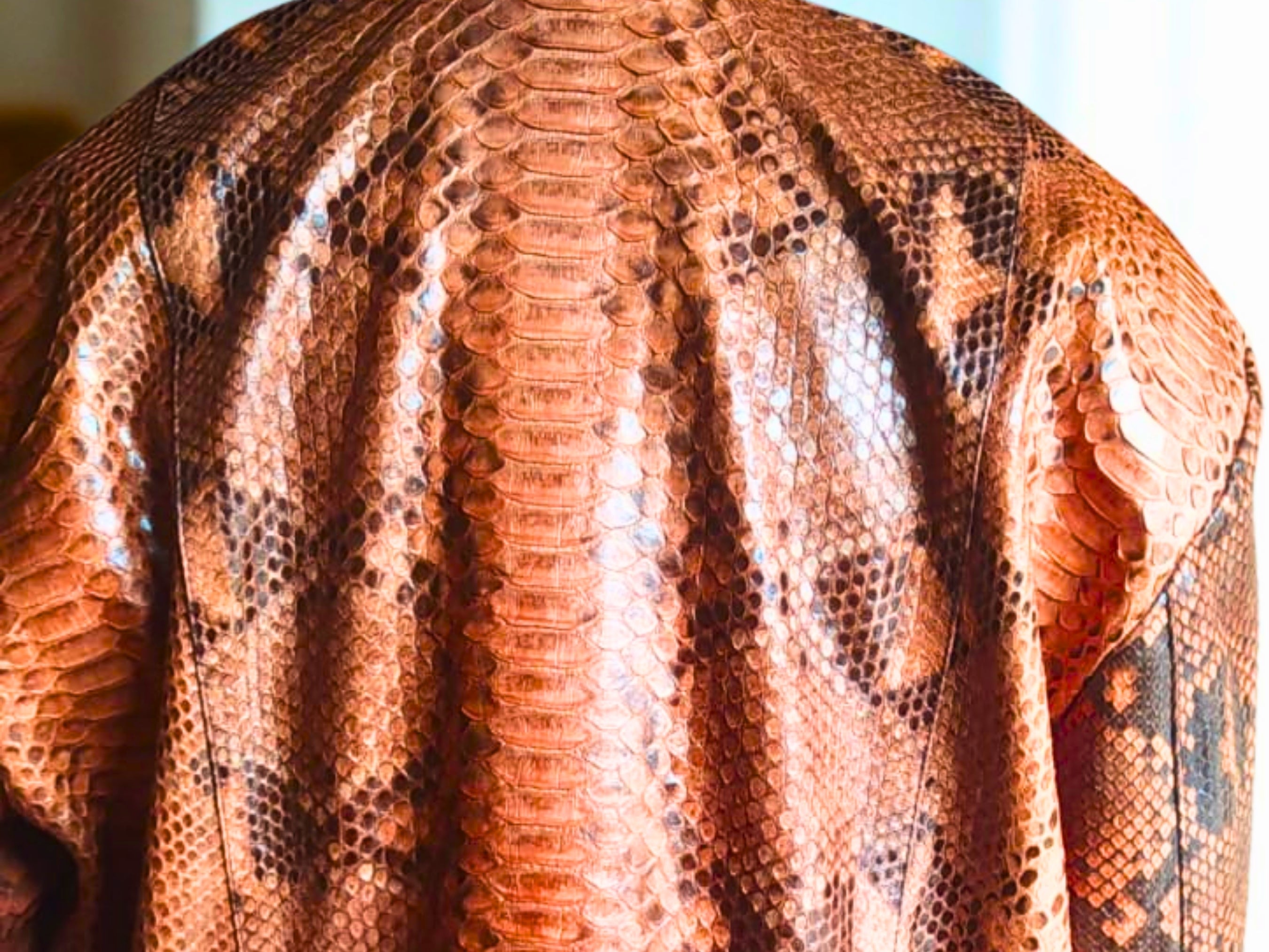 Close-up of brown leather bomber jacket scaly snakeskin texture with raised pattern