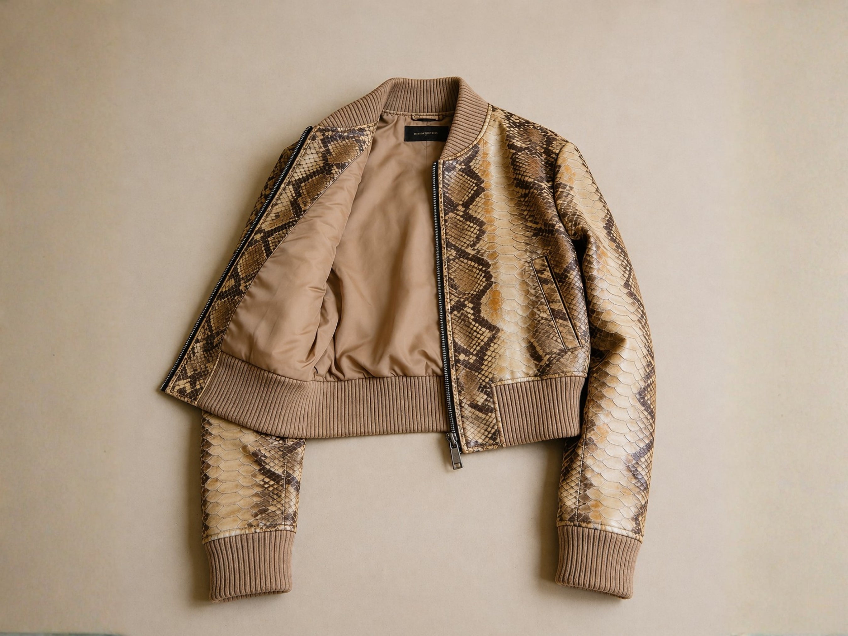 Cropped snakeskin bomber jacket with visible lining, front zip, and ribbed cuffs and hem