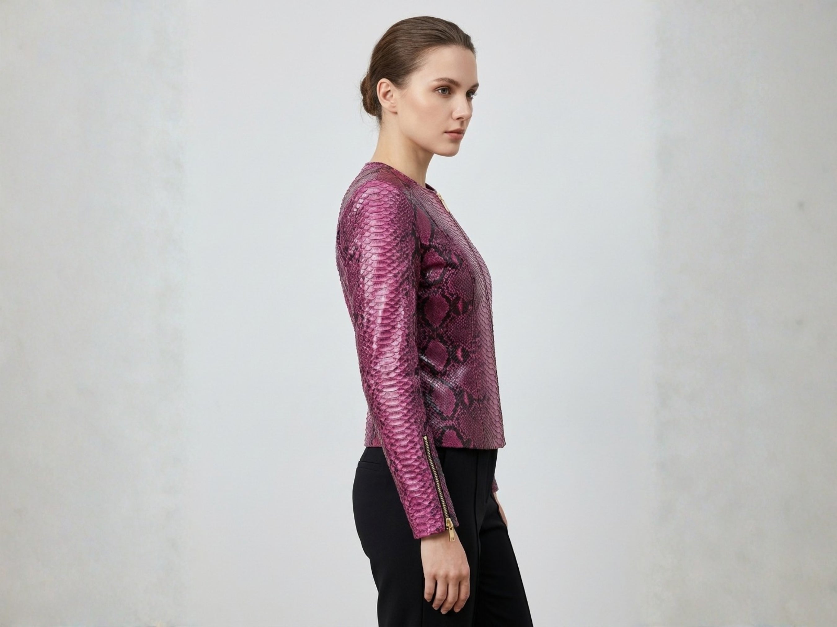 Pink burgundy snakeskin leather jacket on model, side profile, long sleeves and zipper