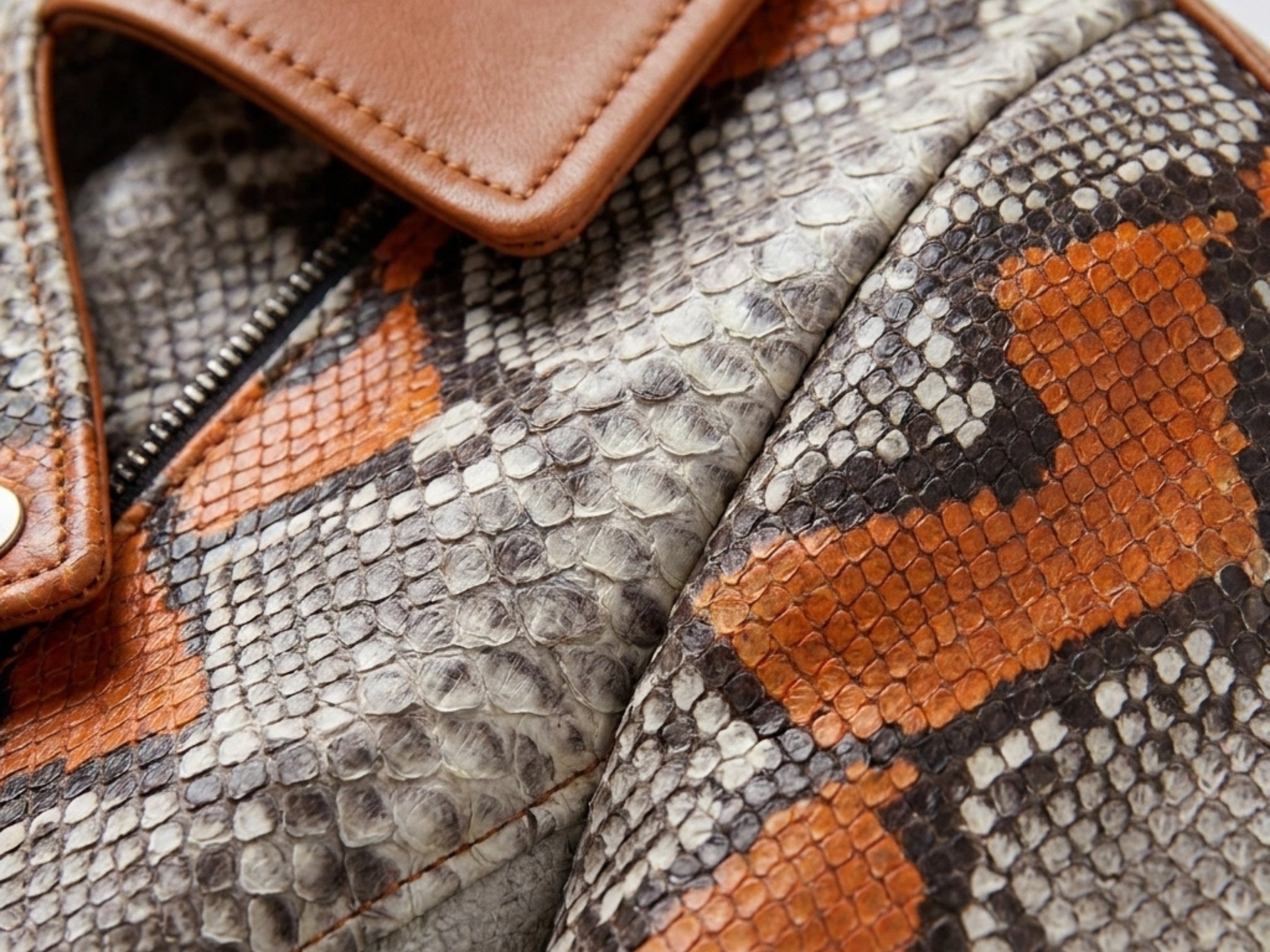 Close-up snakeskin biker leather jacket: textured gray skin with orange scale panels.