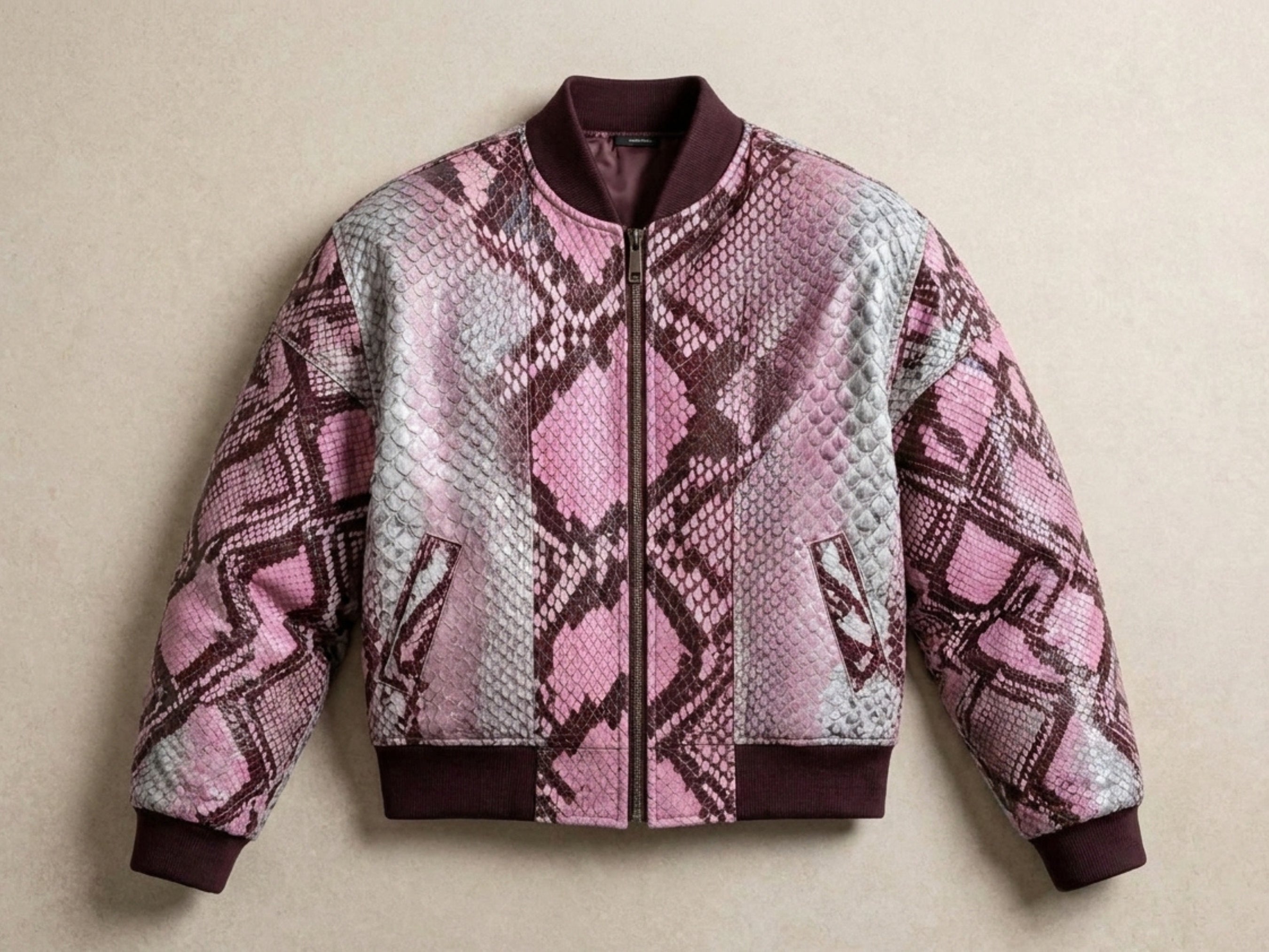 Front-close view of blush pink snakeskin bomber jacket with maroon ribbed trim