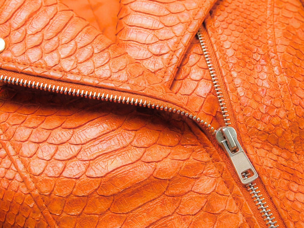 Close-up of burnt orange snakeskin-texture leather with silver zipper track inside panel