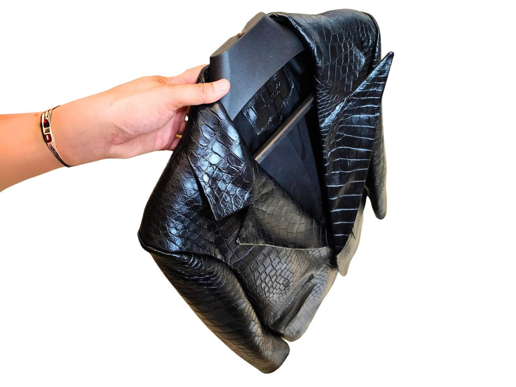 Alligator-skin jacket folded in hand, showing collar and glossy scale-patterned finish.