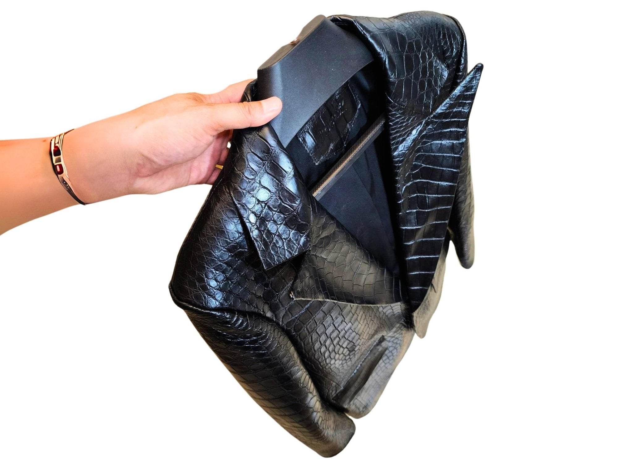Alligator-skin jacket folded in hand, showing collar and glossy scale-patterned finish.