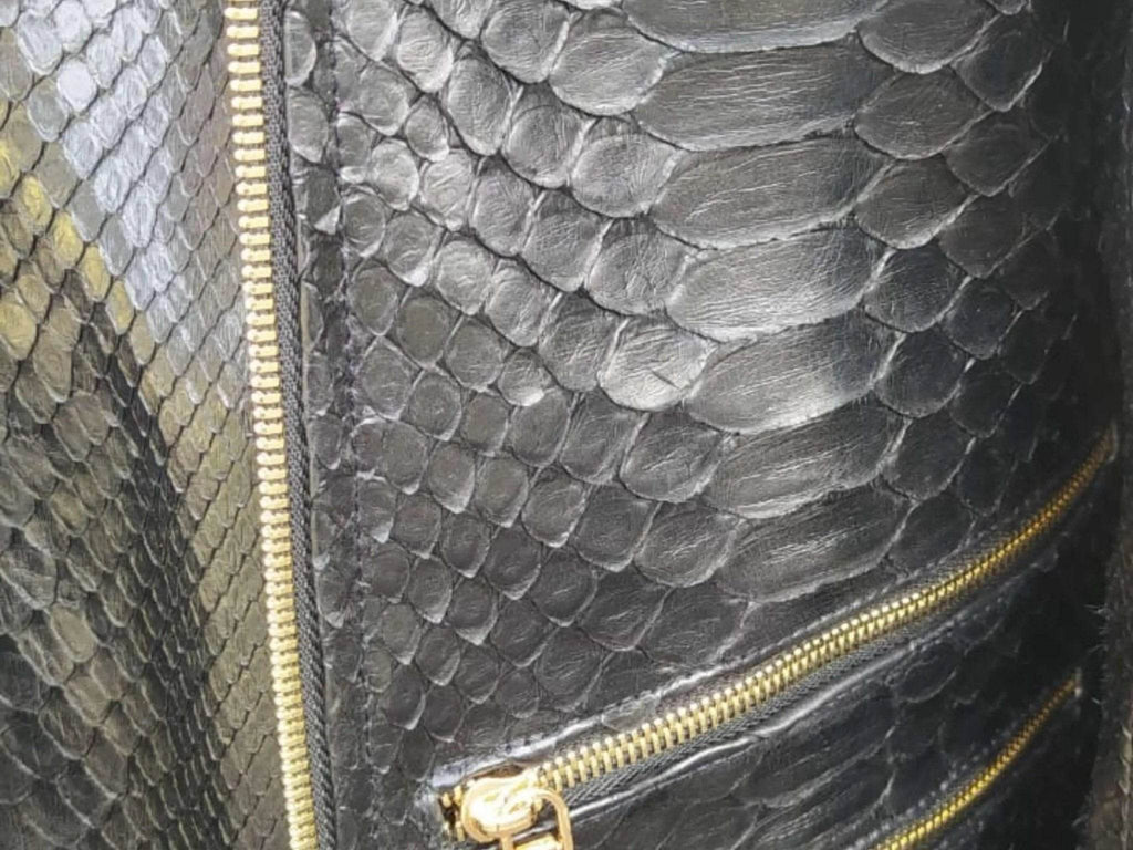 Black snakeskin leather jacket detail: gold zip and textured scale pattern