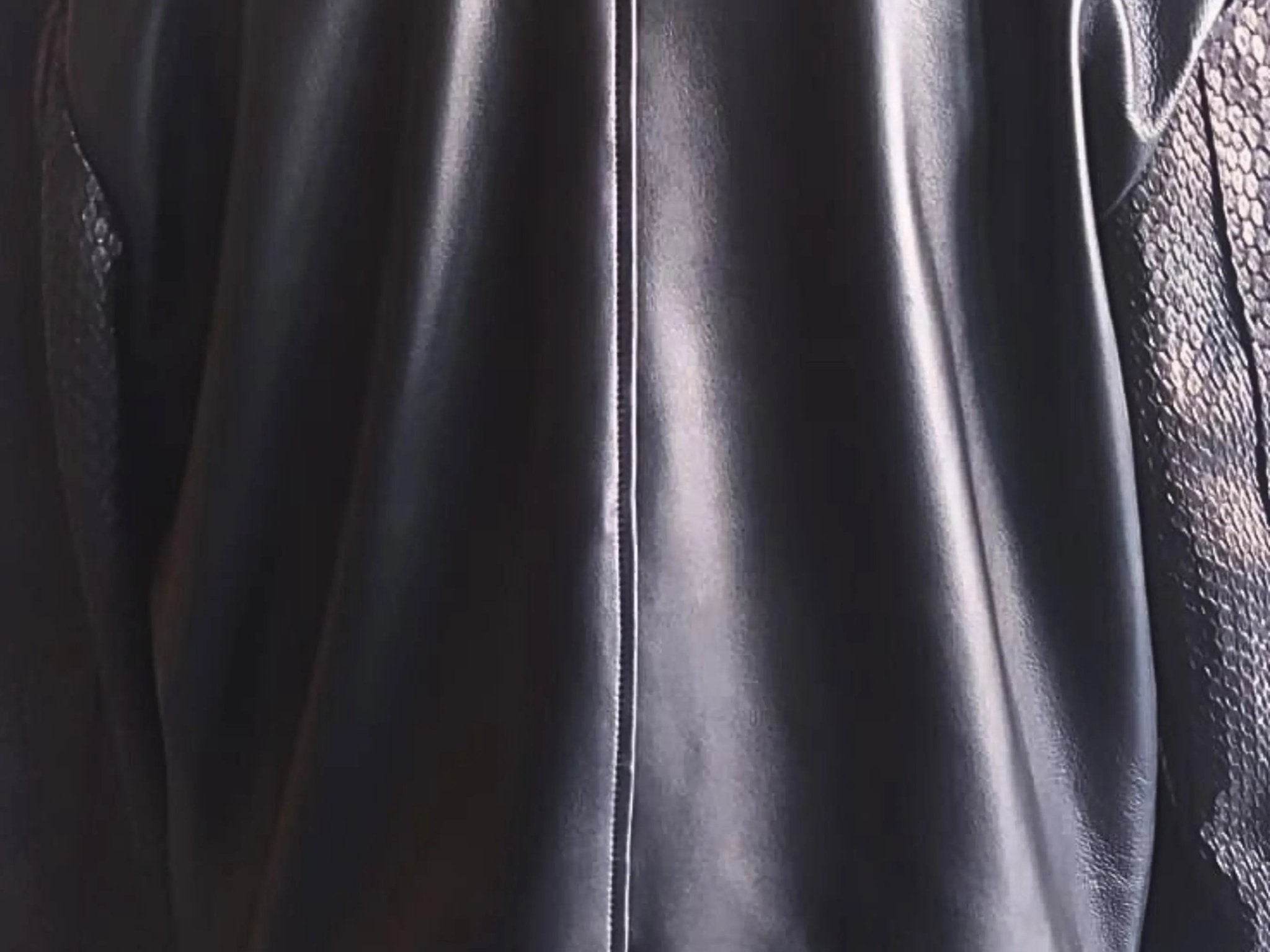 Black leather bomber jacket front panel close-up with zipper and glossy finish