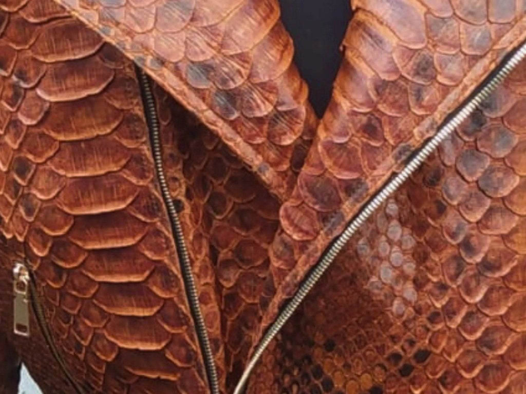 Brown snake-scale leather jacket detail with silver zippers and diagonal seam