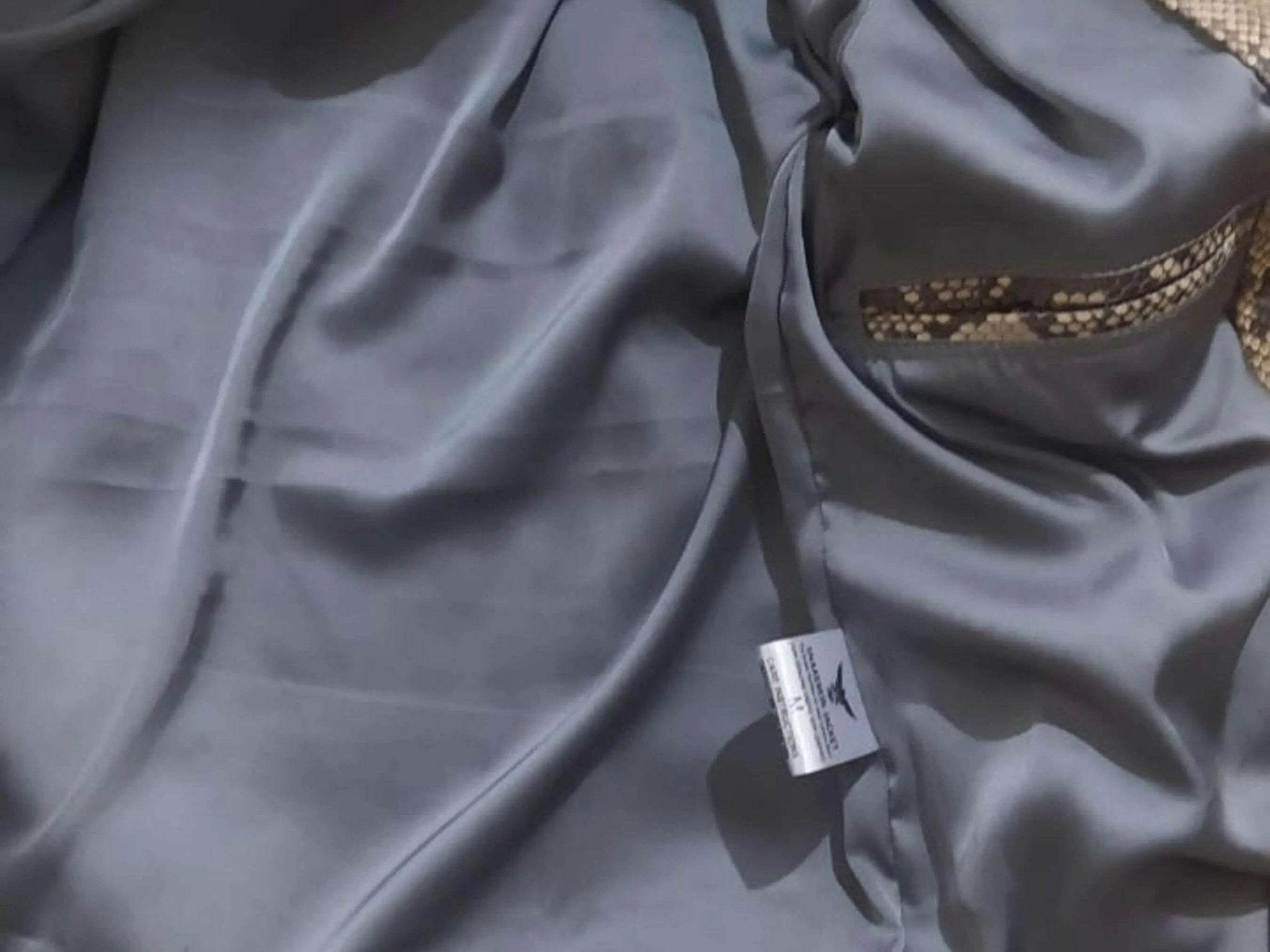 Grey satin-like inner lining fabric detail with label tag inside the jacket