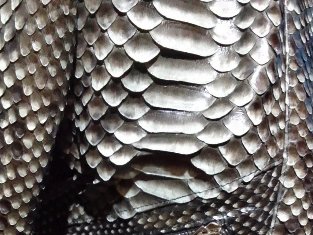 Close-up of metallic scale-pattern leather jacket fabric texture in silver tones