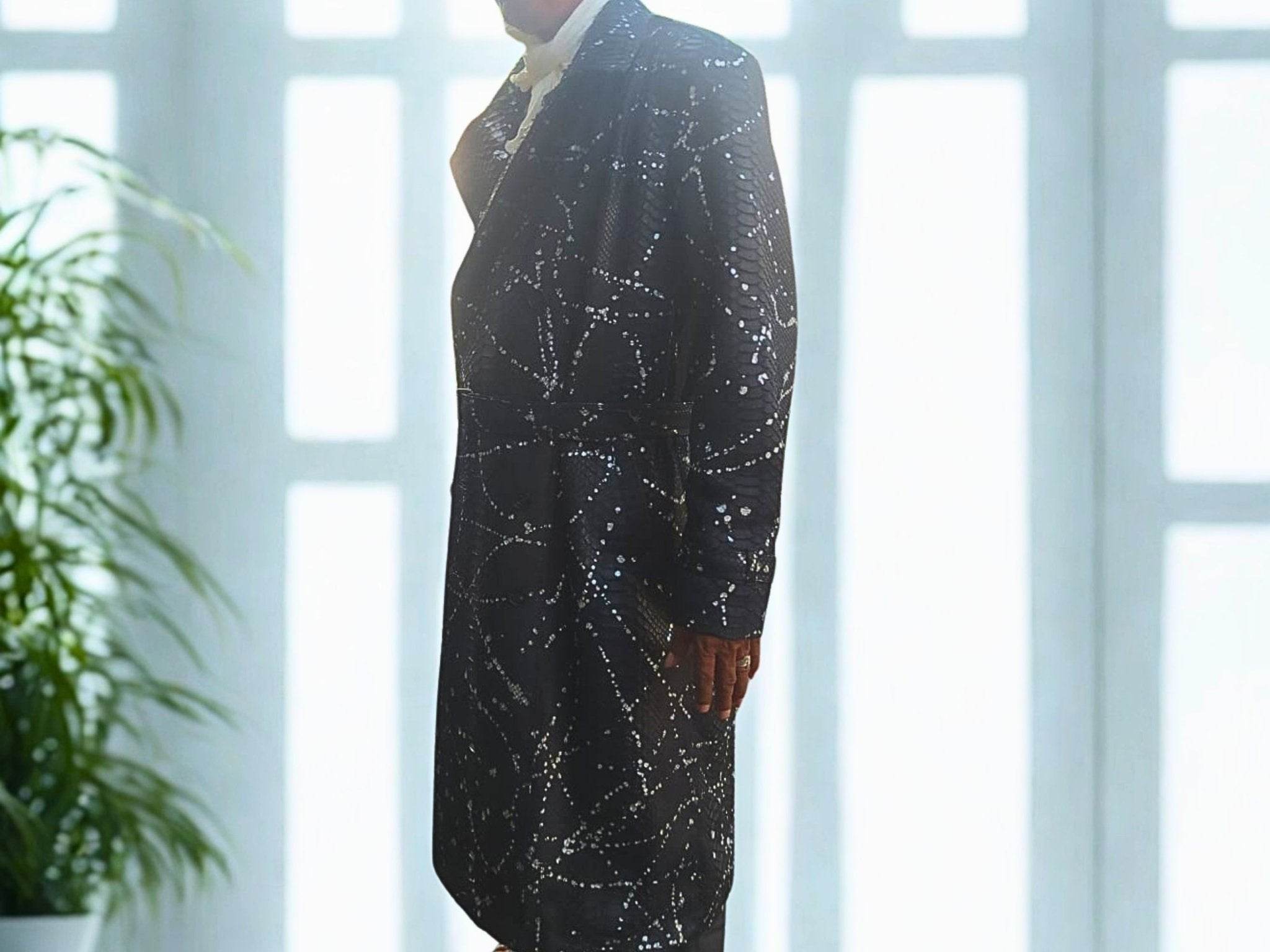 Dark long coat with snakeskin-inspired geometric pattern, side profile and wide sleeves